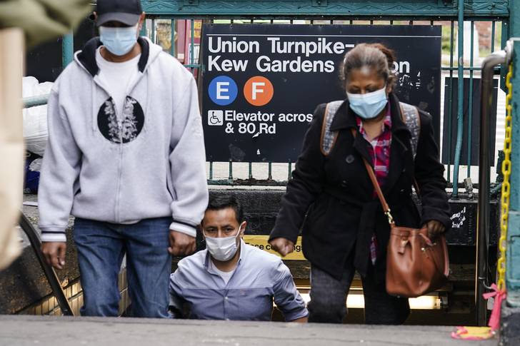 People wearing protective masks during the coronavirus pandemic exit the Kew Gardens subway station.